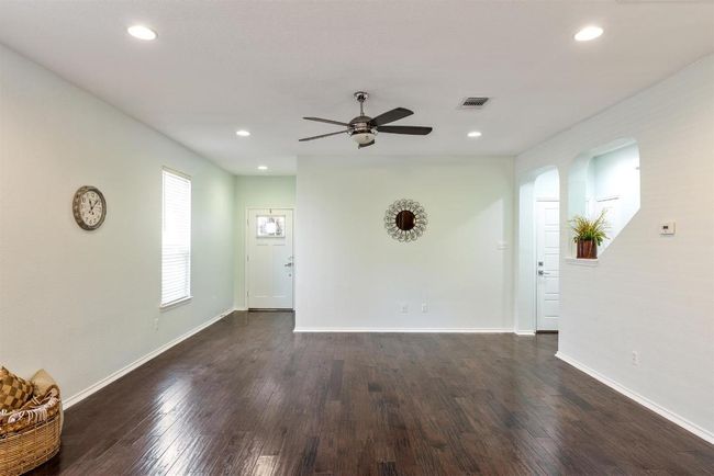 Unfurnished living room with ceiling fan, arched walkways, recessed lighting, and dark wood-style flooring | Image 9