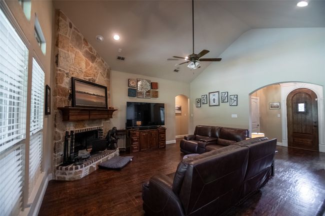 Living area featuring arched walkways, a fireplace, ceiling fan, dark wood finished floors, and high vaulted ceiling | Image 11