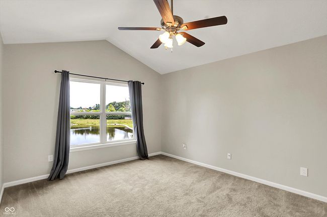 primary bedroom with carpet floors, lofted ceiling, ceiling fan, water view and a massive walk in closet | Image 22