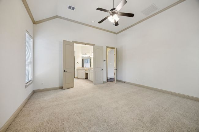 Unfurnished bedroom featuring ornamental molding, light carpet, multiple windows, baseboards, and vaulted ceiling | Image 18