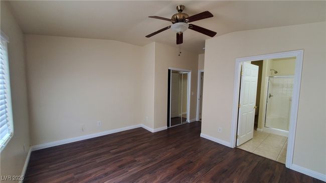 Unfurnished bedroom featuring a ceiling fan, baseboards, vaulted ceiling, and wood finished floors | Image 9
