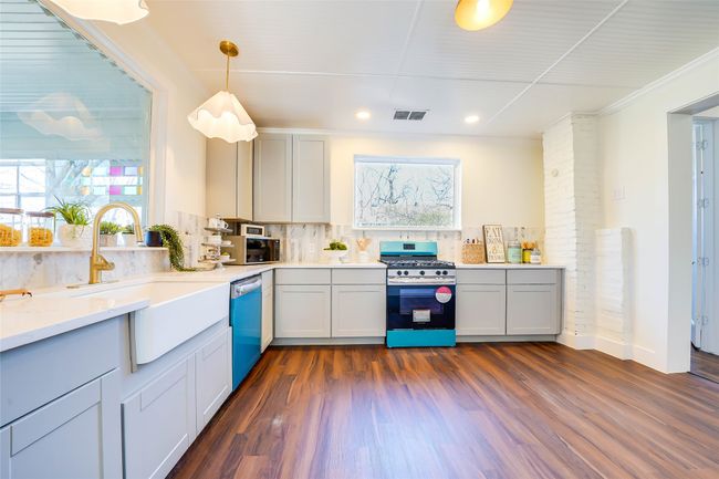 Kitchen with sink, dark wood-type flooring, hanging light fixtures, stainless steel appliances, and decorative backsplash | Image 7