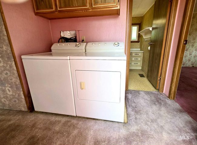 Laundry area featuring washing machine and clothes dryer, cabinet space, and carpet | Image 12