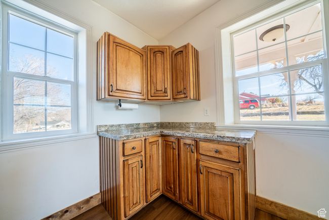 Kitchen with light countertops, brown cabinets, dark wood finished floors, and baseboards | Image 24