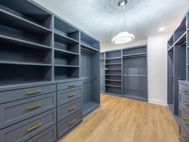 This custom walk-in closet offers the ultimate in organization and style, featuring double-sided built-ins, open shelving, and deep drawer storage for a clutter-free lifestyle. | Image 22