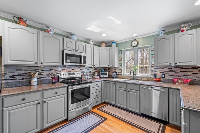 Kitchen with tile backsplash, stainless steel appliances, hardwood floors. | Image 11