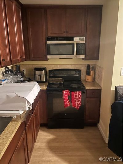 Kitchen with black appliances, light wood-type flooring, and decorative backsplash | Image 2