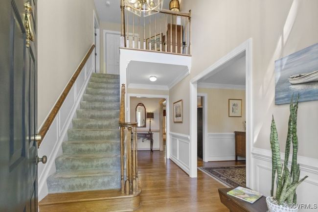 Foyer featuring a chandelier, wood finished floors, stairway, wainscoting, and ornamental molding | Image 8