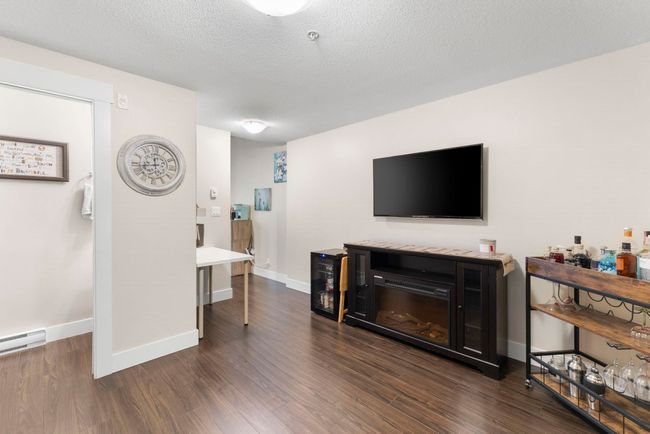 Living area featuring wood finished floors, a textured ceiling, baseboards, and baseboard heating | Image 10