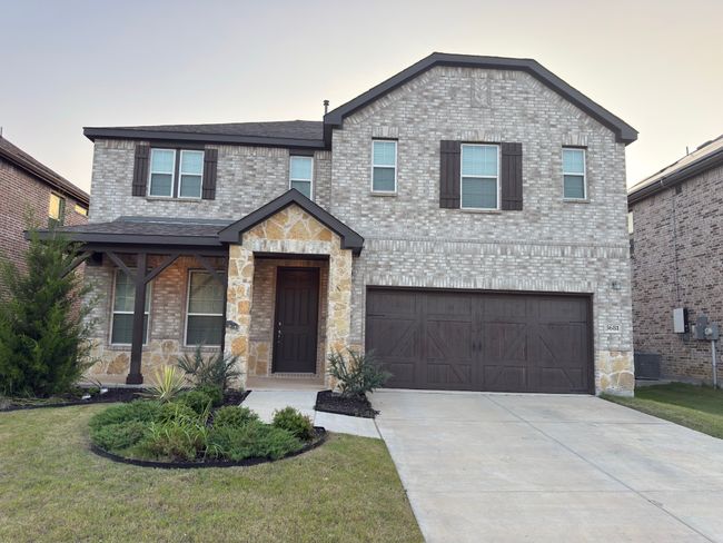 View of front of property with an attached garage, driveway, brick siding, a front lawn, and roof with shingles | Image 23