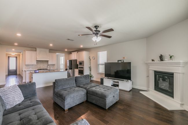 Living room featuring baseboards, ceiling fan, dark wood finished floors, recessed lighting, and a glass covered fireplace | Image 24