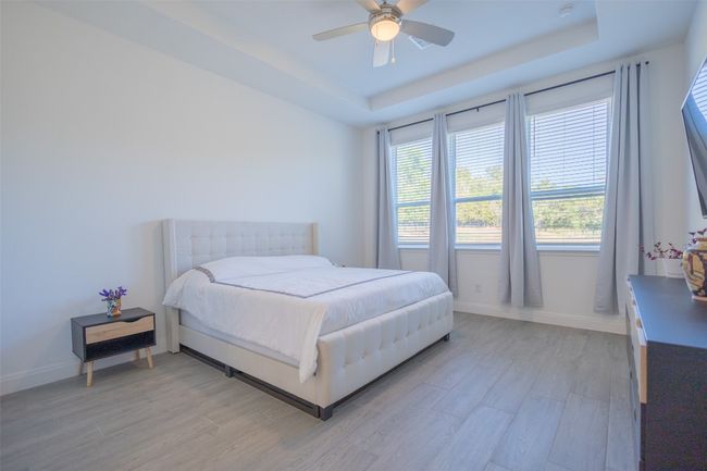 High tray ceilings, a ceiling fan, and several large windows in the Owner's Suite. | Image 18