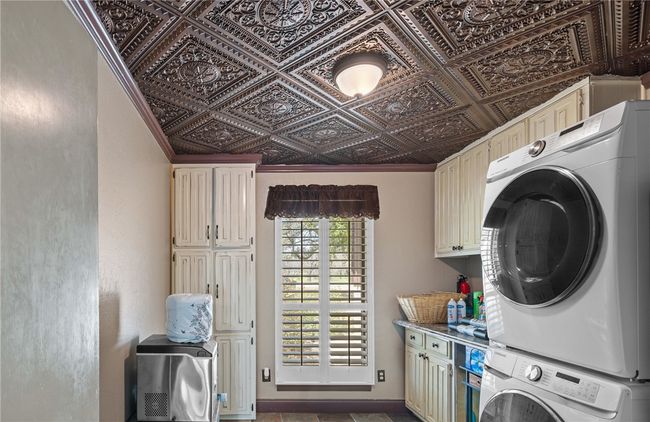 Laundry area featuring cabinet space, an ornate ceiling, and stacked washing maching and dryer | Image 43