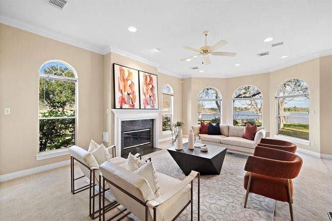 Filled with an abundance of natural light streaming through large arched windows, this casual living area offers a calming view of the waterfront. | Image 16
