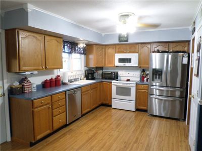 Kitchen with crown molding, ceiling fan, stainless steel appliances, light hardwood / wood-style floors, and sink | Image 2