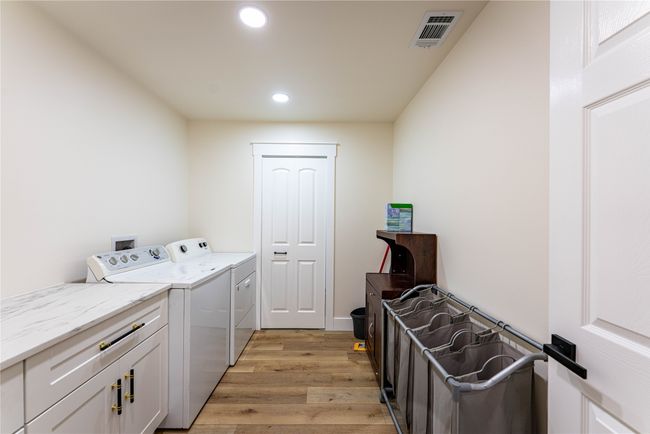 Laundry room with cabinet space, visible vents, washer and dryer, light wood-type flooring, and recessed lighting | Image 13