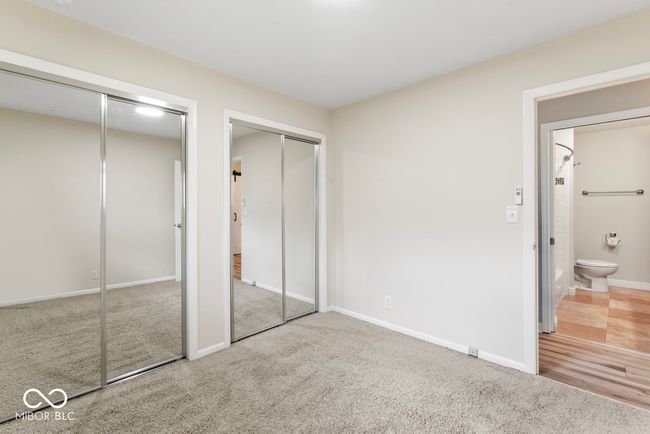 unfurnished bedroom with baseboards, two closets, connected bathroom, and carpet floors | Image 18