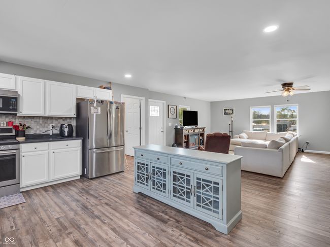 kitchen featuring decorative backsplash, stainless steel appliances, a ceiling fan, and white cabinets | Image 9