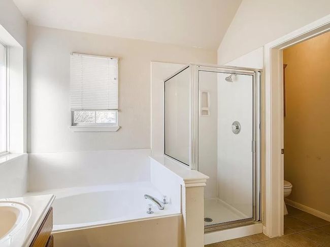 Bathroom with a garden tub, a stall shower, toilet, vanity, and tile patterned floors | Image 19