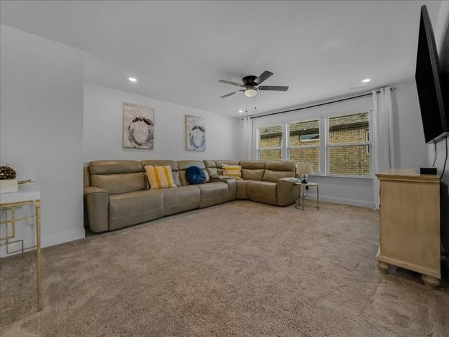 Carpeted living room with ceiling fan, baseboards, and recessed lighting | Image 23
