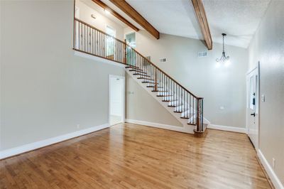 Foyer entrance with light hardwood / wood-style floors, a notable chandelier, beamed ceiling, and high vaulted ceiling | Image 3