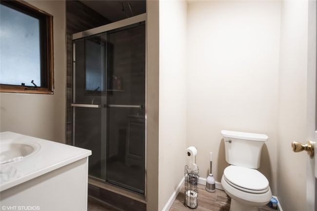 Bathroom featuring toilet, vanity, a stall shower, and wood finished floors | Image 7