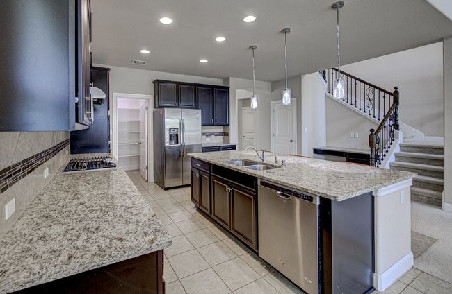 Kitchen featuring stainless steel appliances, decorative backsplash, light tile patterned floors, a kitchen island with sink, and recessed lighting | Image 9