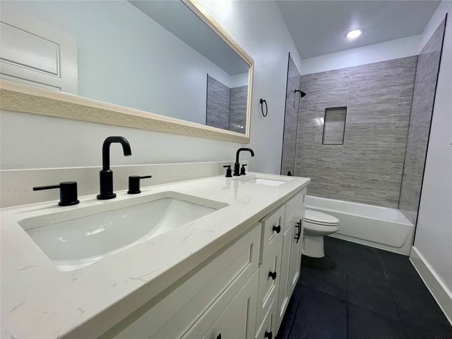 Full bathroom featuring tile patterned floors, toilet, bathing tub / shower combination, double vanity, and baseboards | Image 29