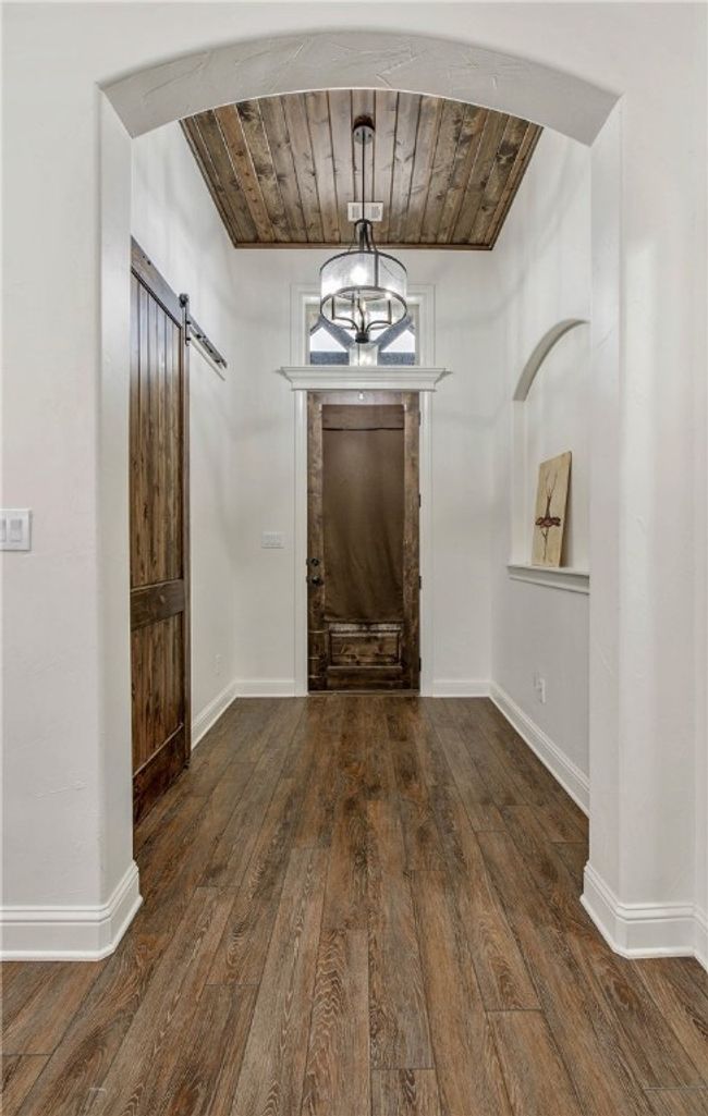 Foyer featuring a barn door, hardwood / wood-style flooring, wood ceiling, and baseboards | Image 5