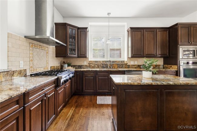 10' Ceilings, Surround sound, Island with storage, Kitchen Aid 5 burner gas range, Kitchen aid wall oven, Whirpool wall microwave, Kitchen aid stainless steel refrigerator and dishwasher, Granite countertops, Recessed and pendant lighting, Double bowl stainless sink, corner pantry, decorative tile behind the range, tile backsplash, bar seating. | Image 11