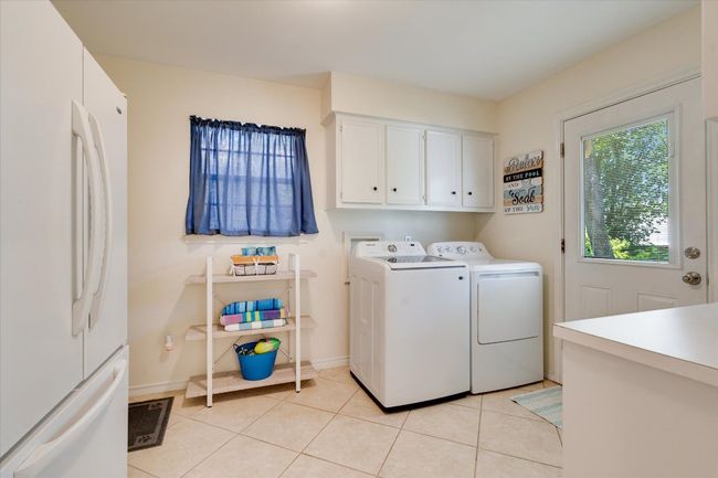 Washroom featuring washer and dryer, cabinet space, light tile patterned floors, and baseboards | Image 18