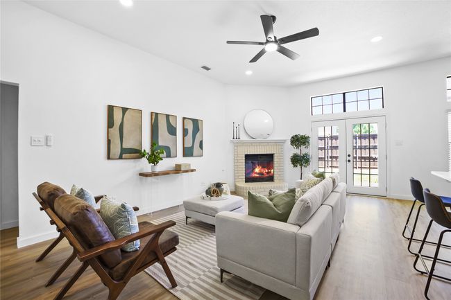 Living room with wood finished floors, a fireplace, recessed lighting, a ceiling fan, and french doors | Image 6