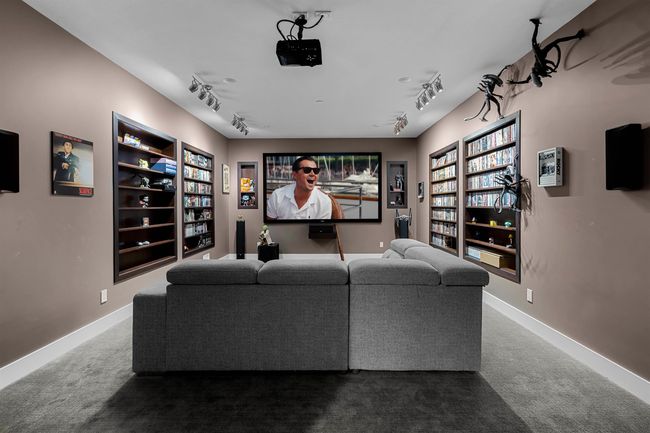 Carpeted home theater room featuring built in shelves, rail lighting, and baseboards | Image 28