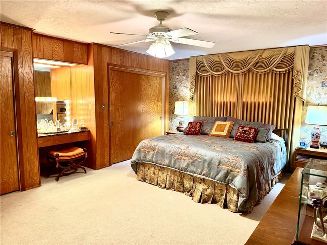 Carpeted bedroom featuring a textured ceiling, ceiling fan, and wood walls | Image 30
