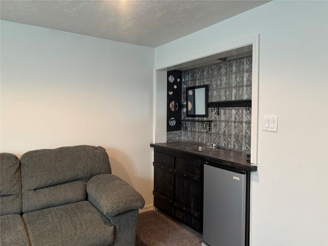 Indoor wet bar featuring freestanding refrigerator, carpet flooring, and baseboards | Image 21