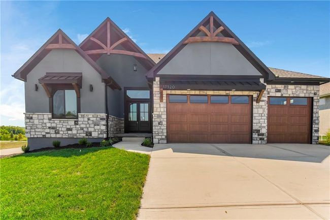 View of front of house with stone siding, stucco siding, a front lawn, concrete driveway, and a garage | Image 4