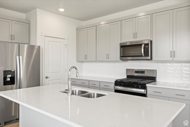 Kitchen with appliances with stainless steel finishes, gray cabinetry, tasteful backsplash, recessed lighting, and an island with sink | Image 22