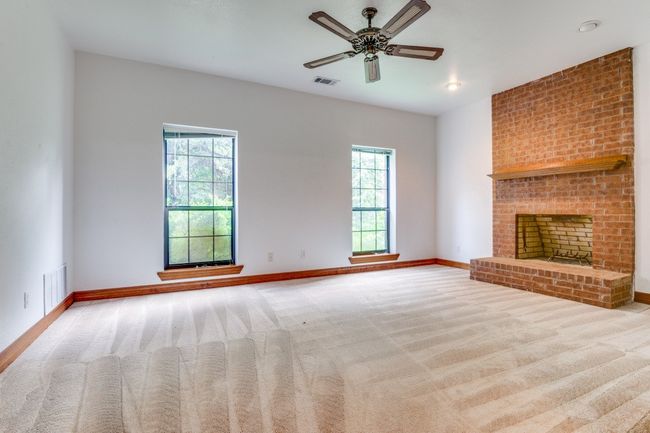 Unfurnished living room with carpet floors, ceiling fan, and a brick fireplace | Image 6