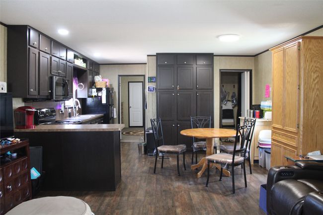 Kitchen featuring black appliances, dark wood-type flooring, a sink, and a peninsula | Image 28