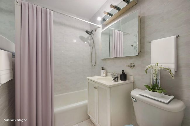 Full bathroom featuring tile walls, vanity, toilet, and shower / tub combo | Image 8