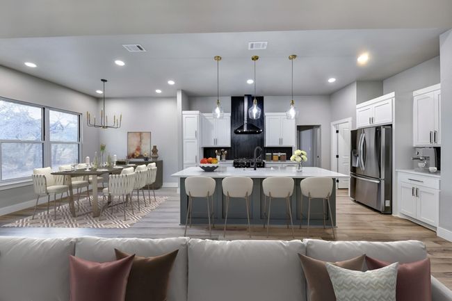 Kitchen with white cabinetry, hanging light fixtures, wall chimney range hood, stainless steel refrigerator with ice dispenser, and an island with sink | Image 5