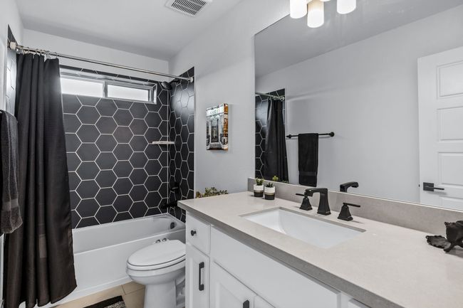 Full bathroom with tile patterned floors, vanity, toilet, and shower / bath combination with curtain | Image 25