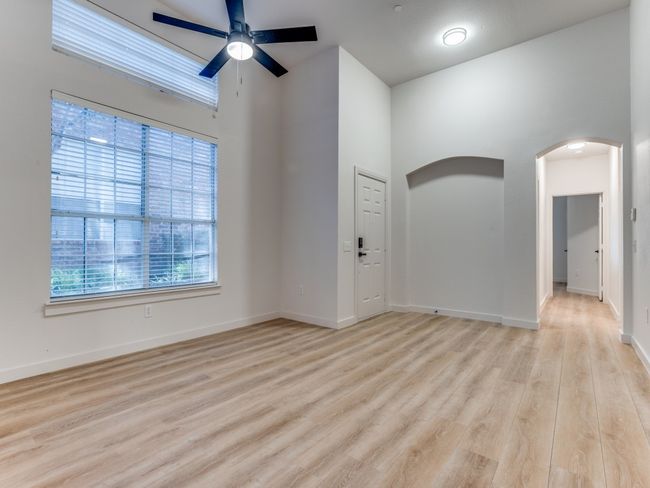 Spare room with ceiling fan, arched walkways, light wood finished floors, and a high ceiling | Image 4
