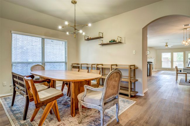 Dining space with visible vents, baseboards, arched walkways, light wood-style floors, and ceiling fan with notable chandelier | Image 8