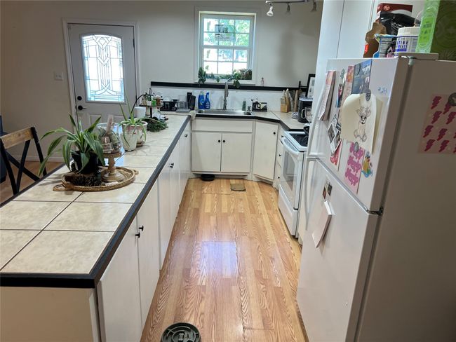 Kitchen with white appliances, a sink, light wood-type flooring, white cabinets, and a peninsula | Image 12