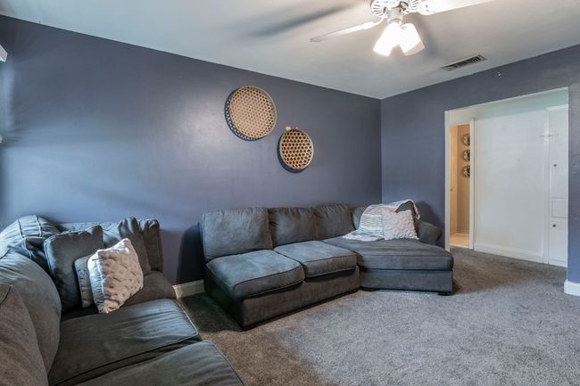 Living area with ceiling fan, carpet flooring, and baseboards | Image 7