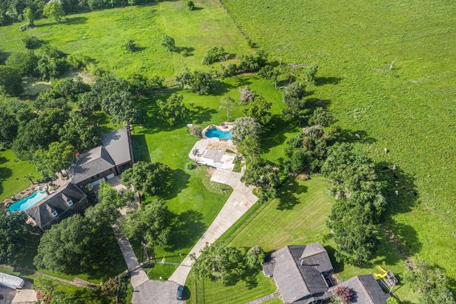 The long driveway curves gracefully toward the center of the property, adding to the estate-like feel. This image highlights the perfect blend of resort-style living and serene countryside views. | Image 8