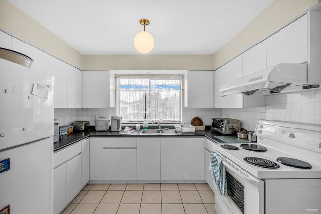 Kitchen featuring white appliances, dark countertops, under cabinet range hood, and decorative backsplash | Image 11