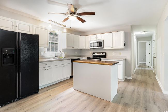 Kitchen featuring white cabinets, a ceiling fan, appliances with stainless steel finishes, and a sink | Image 7