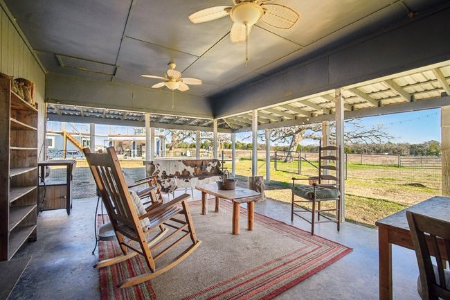 Expansive back porch - great view overlooking the southeast direction of the property - the row crops between the house and the highway, and the guest house/outdoor kitchen area. | Image 14